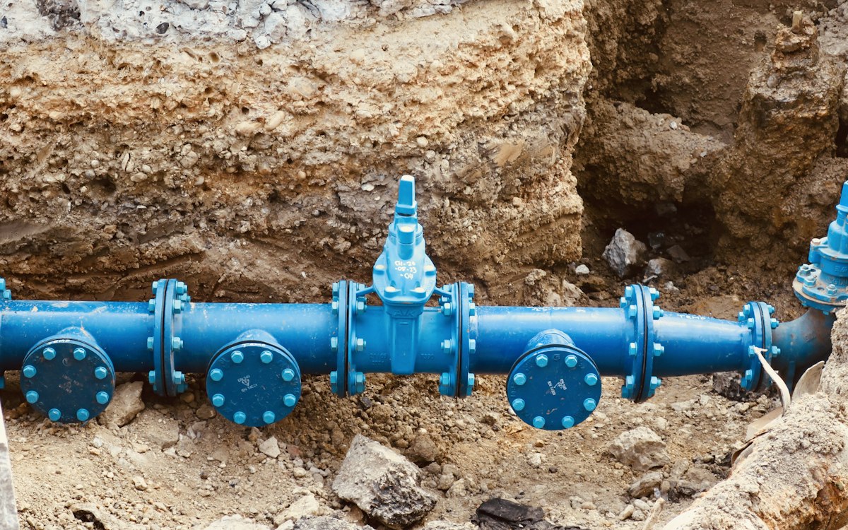 Tubería azul de agua potable con válvulas instalada en zanja